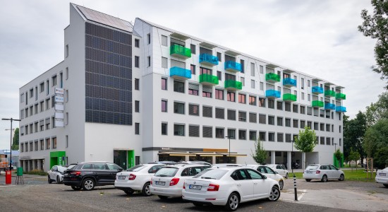 Inovační centrum SVATOPETRSKA od jihozápadu - v 1.NP Bernard Pub a zázemí, 3 patra kanceláří, 2 patra bytů; v popředí kapacitní parkoviště | Výsledek rekonstrukce - r.2020